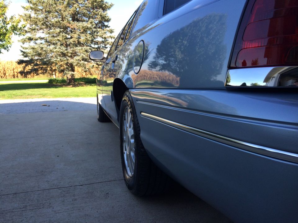 Light blue sedan rear quarter panel with chrome trim and taillight visible. 2003 Ford Crown Victoria