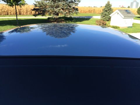 2003 Ford Crown Victoria - Car roof reflects a rural landscape with trees, a cornfield, and a small white building.