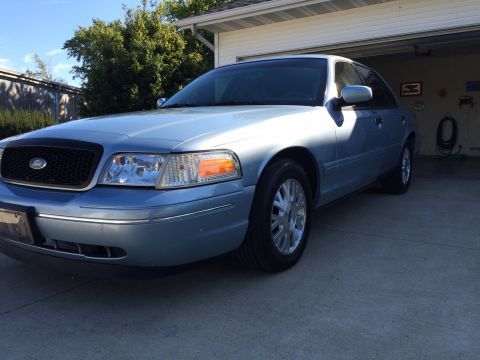 2003 Ford Crown Victoria - A light blue 2003 Ford Crown Victoria sedan is parked in a driveway.