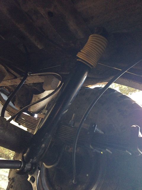 1979 Ford Bronco - Close-up view of a vehicle's undercarriage components, including a shock absorber and leaf springs.