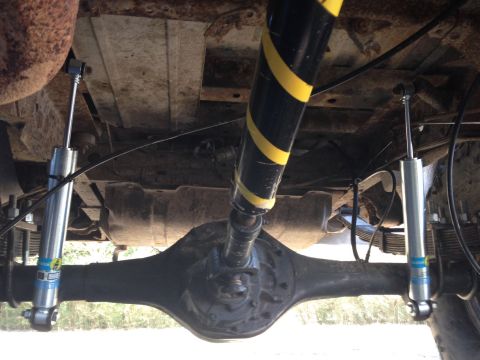 1979 Ford Bronco - Undercarriage view shows the rear axle, driveshaft, and shocks, including a yellow-striped shock absorber.