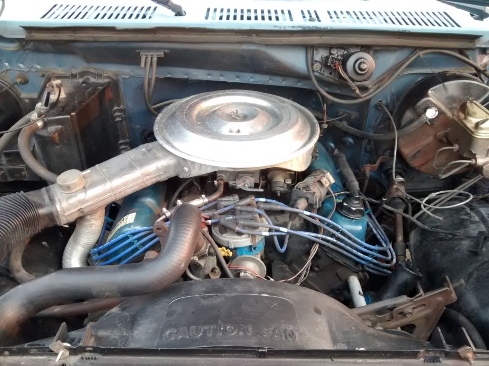 Engine bay with air cleaner, distributor, and hoses visible. 'CAUTION FAN' text on shroud