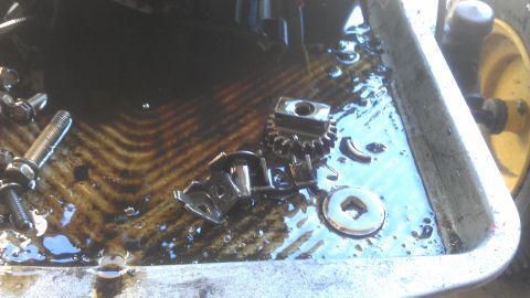 2006 Honda RANCHER - Various engine components soaking in used oil within a pan.