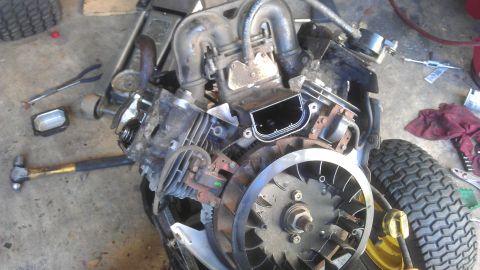 2006 Honda RANCHER - A disassembled lawn mower engine sits on a concrete floor with tools scattered around it.