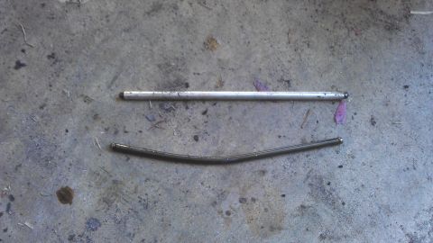 2006 Honda RANCHER - Two metal rods, one bent and one straight, lie on a concrete surface.
