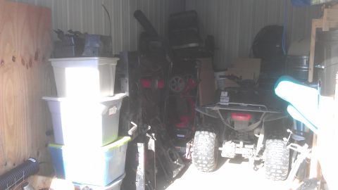 2006 Honda RANCHER - Rear view of a black all-terrain vehicle parked inside a storage unit, surrounded by various items.