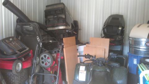 2006 Honda RANCHER - A storage unit contains a green four-wheeler, two lawnmowers, and several engine parts.