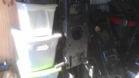 2006 Honda RANCHER - Storage bins sit next to a disassembled lawn mower frame in a cluttered area.