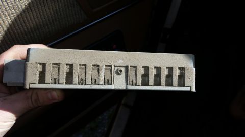 1991 Ford F-250 - A dusty electronic control module is held in a hand, showing its connector and slotted casing.