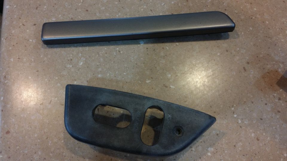 Two dark gray interior trim pieces on a speckled countertop