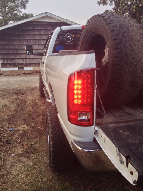 1979 Ford Bronco - A white pickup truck is shown from the rear, modern LED tail lights and a large spare tire stowed in the bed.