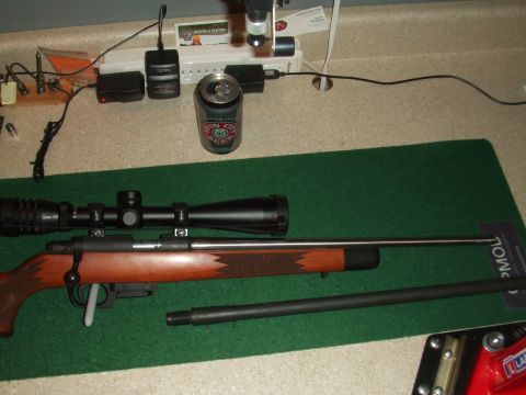 1996 Ford Bronco - A rifle, scope, and spare barrel are laid out on a mat next to a can of beer and some electronic chargers.
