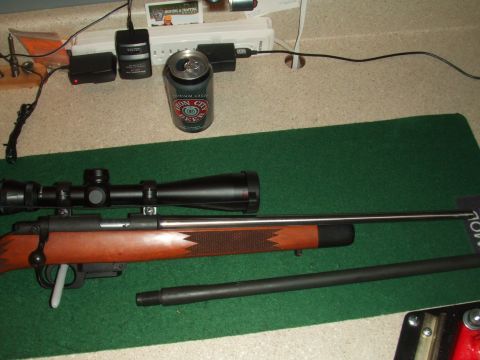 1996 Ford Bronco - A rifle, scope, and extra barrel are laid out on a green mat with a beer and electronics.