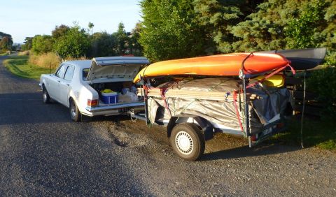 1969 Lincoln Continental - A white sedan is hitched to a trailer carrying kayaks and camping supplies, ready for an outdoor adventure.