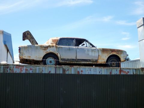1969 Lincoln Continental - This heavily rusted sedan sits abandoned, its trunk lid propped open against the sky.