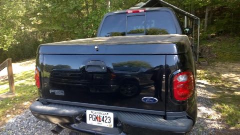 2003 Ford F-150 - Black 2003 Ford F-150 pickup truck parked outdoors with a tonneau cover and Georgia license plate.