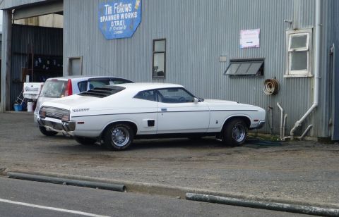 1969 Lincoln Continental - A white coupe with a distinctive louvred rear window is parked outside a workshop.