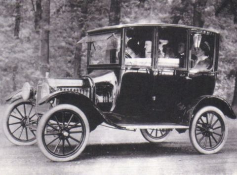 1915 Ford Model T - This vintage touring car features an enclosed passenger compartment and large spoked wheels, typical of early automotive design.