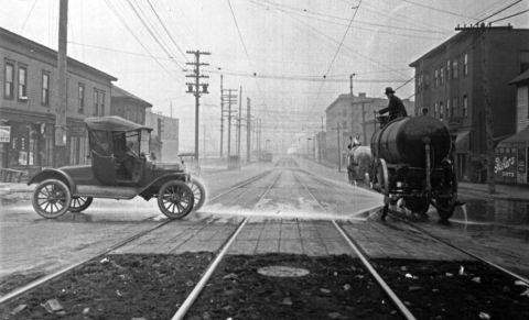 1915 Ford Model T - A street cleaning scene from the early 1900s, showing a truck and a horse-drawn water wagon.