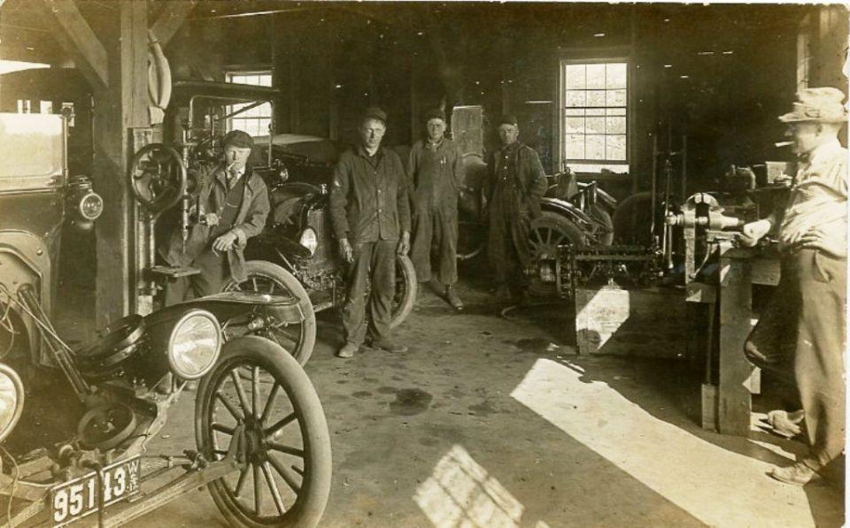 1915 Ford Model T in a garage with men and machinery