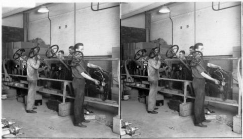 1915 Ford Model T - Workers are seen assembling engines on a factory line, with steering wheels attached to the engine assemblies.