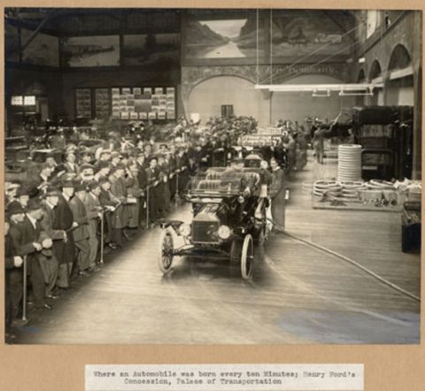 1915 Ford Model T - A 1915 Ford Model T is displayed in a busy dealership or exhibition hall, with many onlookers.