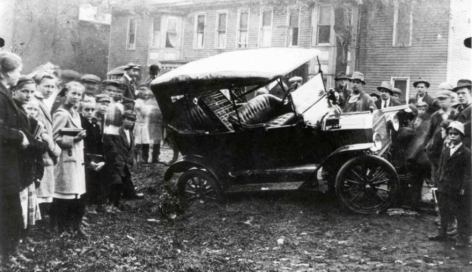 1915 Ford Model T touring car surrounded by a crowd of onlookers