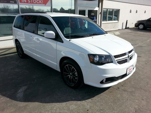 2007 Dodge Durango - A white minivan is parked in front of a building with a dealership sign.
