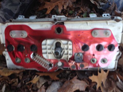 1979 Ford Bronco - A vehicle's dashboard instrument cluster, viewed from the back, rests on a bed of autumn leaves.