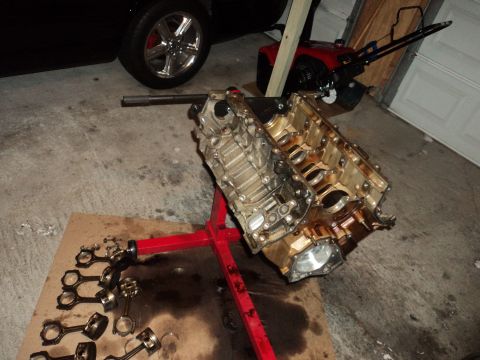2004 Mercury Grand Marquis - Engine block and associated parts are on a stand in a garage, with a vehicle wheel and snowblower visible.