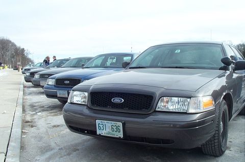 1991 Ford LTD Crown Victoria - A line of Ford Crown Victoria police cars are parked in a lot on a cloudy day.
