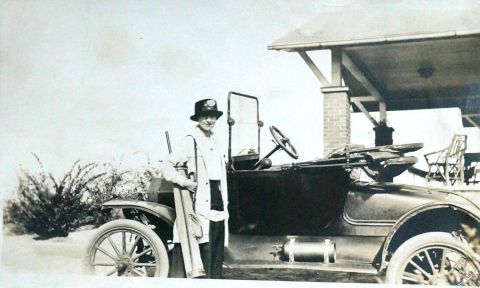 1915 Ford Model T - A woman poses with a vintage automobile, possibly a touring car, under a covered structure.