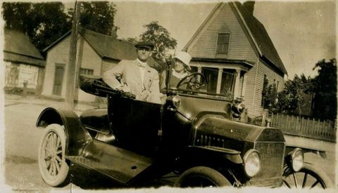 1915 Ford Model T - A couple poses in their 1915 Ford Model T runabout on a residential street.