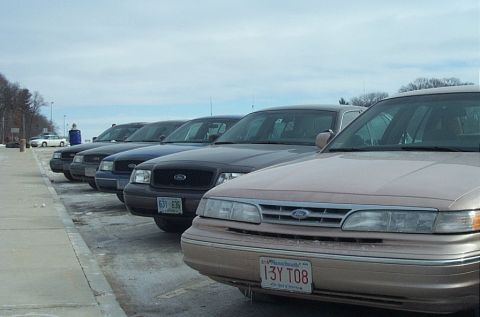 1991 Ford LTD Crown Victoria - Several Ford Crown Victorias are parked in a lot under a cloudy sky.