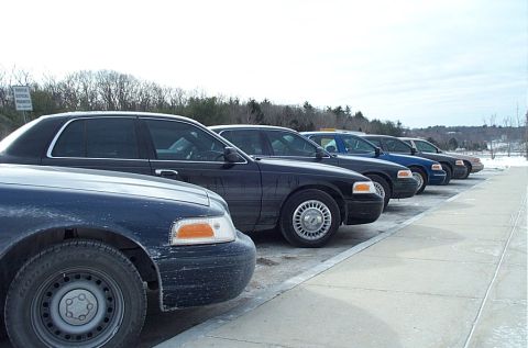 1991 Ford LTD Crown Victoria - Several dark-colored Ford Crown Victoria LTD sedans are parked in a row on a cloudy day.