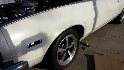 1976 Ford Ranchero - The front fender of a white coupe is shown with the hood open, revealing the engine compartment.