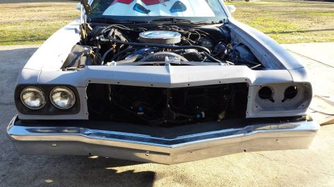 1976 Ford Ranchero - The front of a gray 1972 Ford Ranchero is shown with its hood open, revealing the engine and a missing grille.