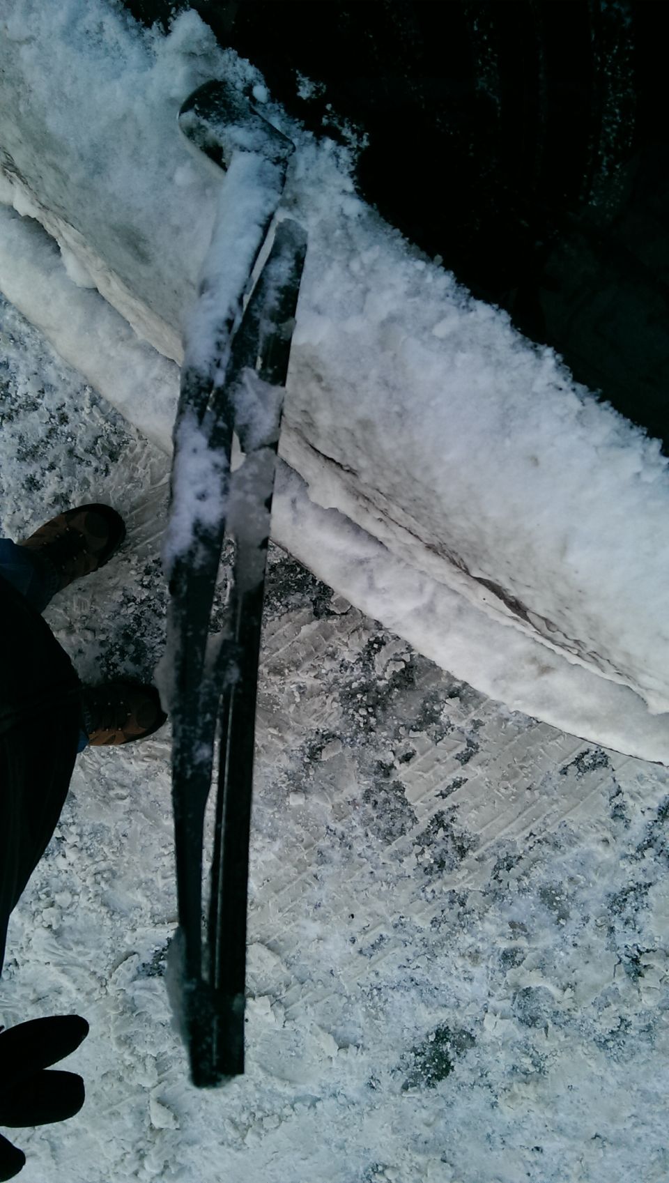 Windshield wipers covered in ice and snow. A hand is visible on the left