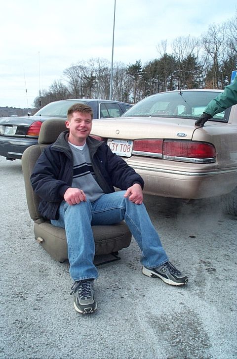 1991 Ford LTD Crown Victoria - A man sits on a car seat in front of a 1991 Ford Crown Victoria LTD, with another car visible behind it.