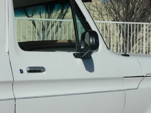 1979 Ford Bronco - The side profile of a white 1979 Ford Bronco is visible, including its door, mirror, and trim details.