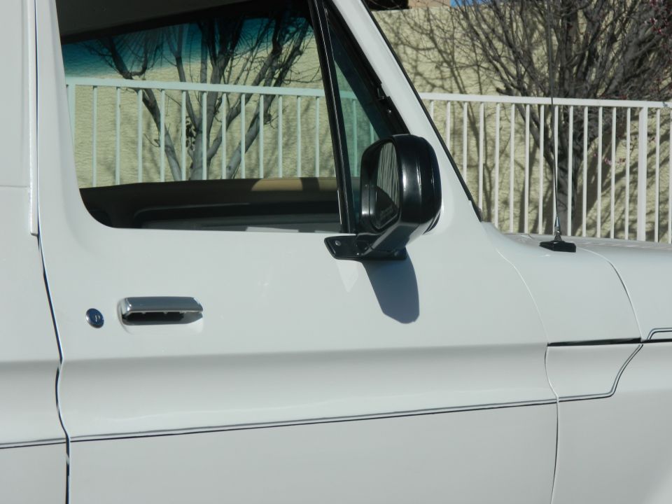 White 1979 Ford Bronco side view showing door handle, side mirror, and pinstripe