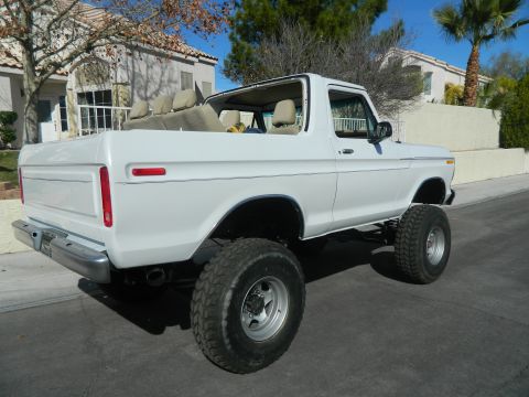 1979 Ford Bronco - This white 1979 Ford Bronco features a removable top and a lifted suspension, seen from the rear three-quarter angle.