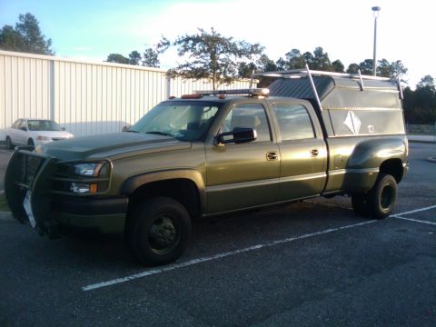 1994 Ford Bronco - Dually pickup truck with a utility cap and brush guard is parked in a lot next to a white sedan.