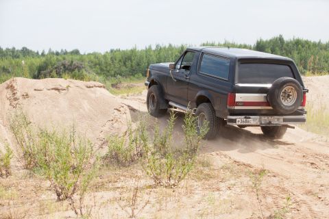 1987 Ford Bronco - This black 1987 Ford Bronco kicks up dust as it navigates a sandy incline.