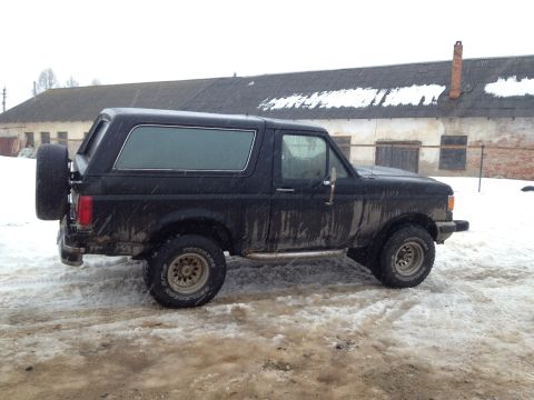 1987 Ford Bronco - Black 1987 Ford Bronco in a snowy outdoor setting with a building in the background.