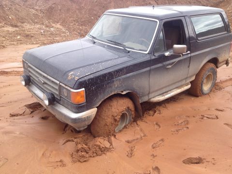 1987 Ford Bronco - This 1987 Ford Bronco is stuck in the mud, with its front driver's side wheel deep in the mire.