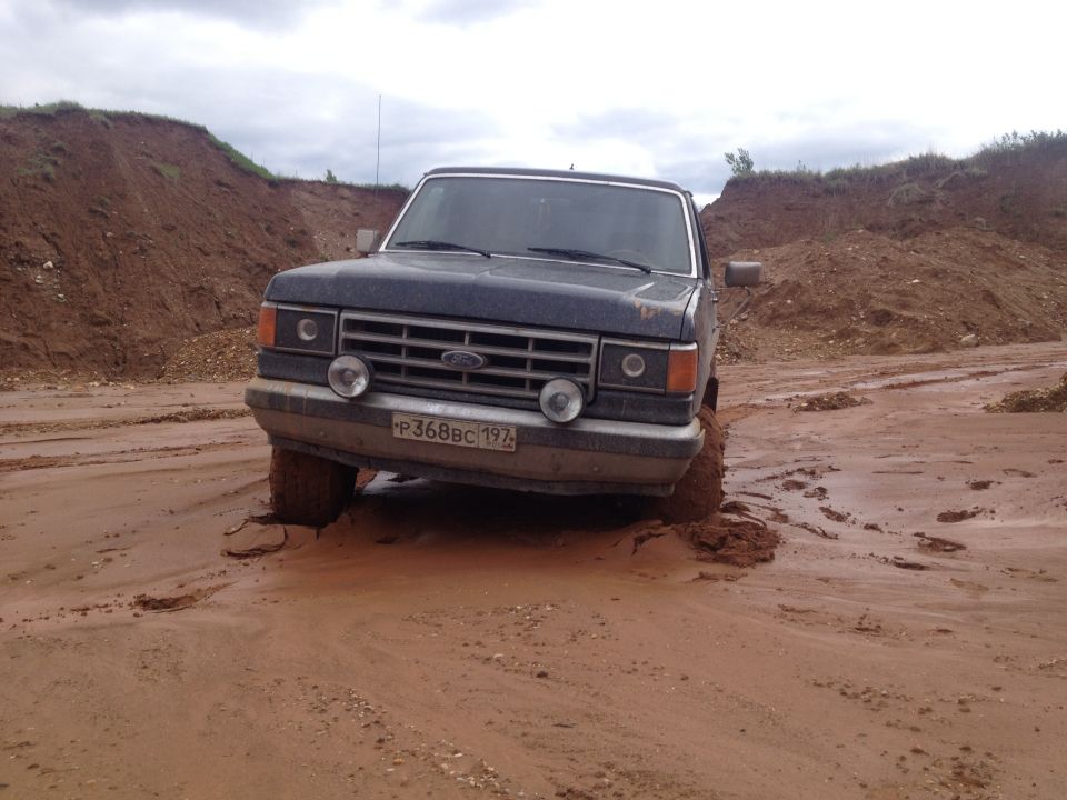 Dark blue 1987 Ford Bronco stuck in mud, front view