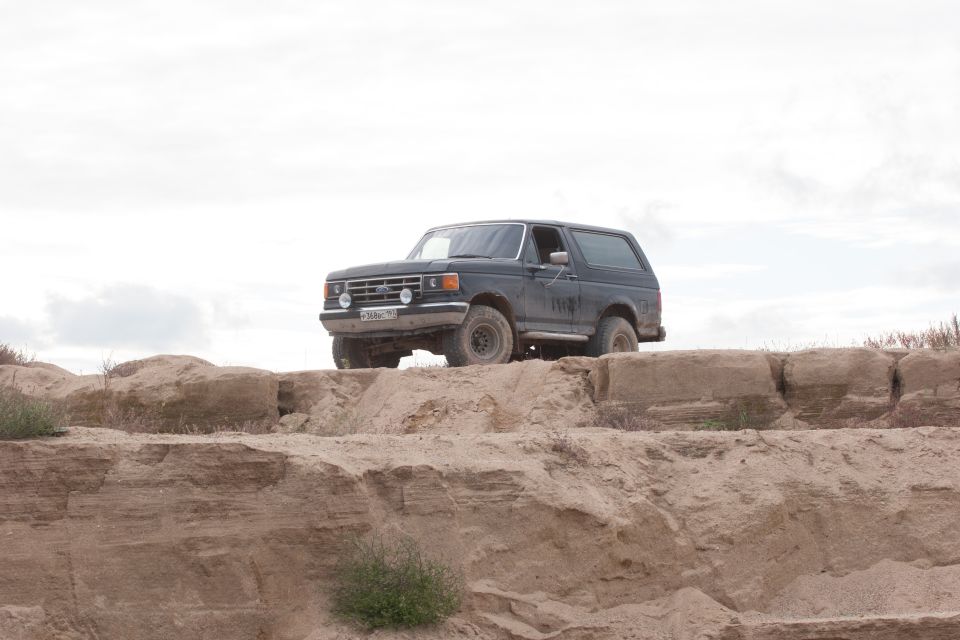 Dark Ford Bronco parked on a dirt mound