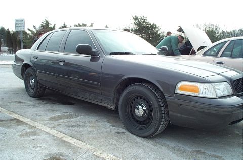 1991 Ford LTD Crown Victoria - A dark gray sedan is parked on a lot, with its hood open and people gathered around.