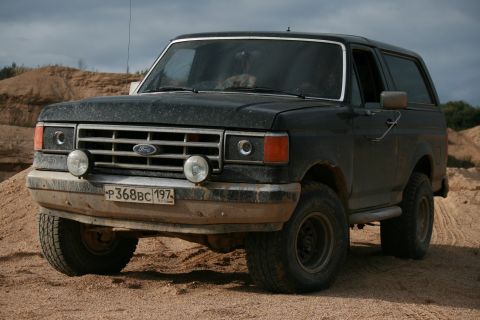 1987 Ford Bronco - This 1987 Ford Bronco is shown from the front-three-quarter view on a sandy terrain.
